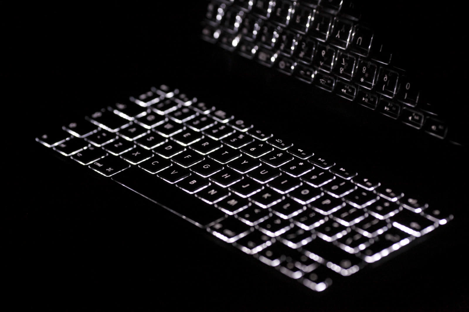 A backlit laptop keyboard photographed in the dark.